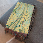 Kök Stüdyo woven cotton throw blanket with abstract pastel marbling art in yellow, green, and blue hues.