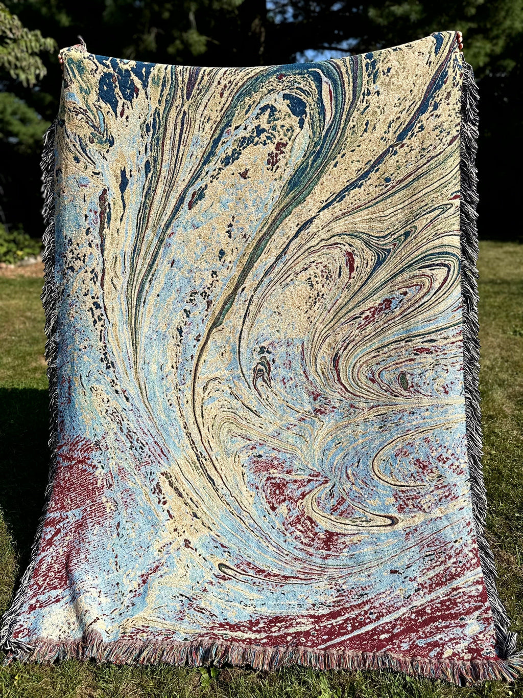 Kök Stüdyo woven cotton throw blanket with abstract pastel blue, cream, and maroon Ebru marbling pattern.