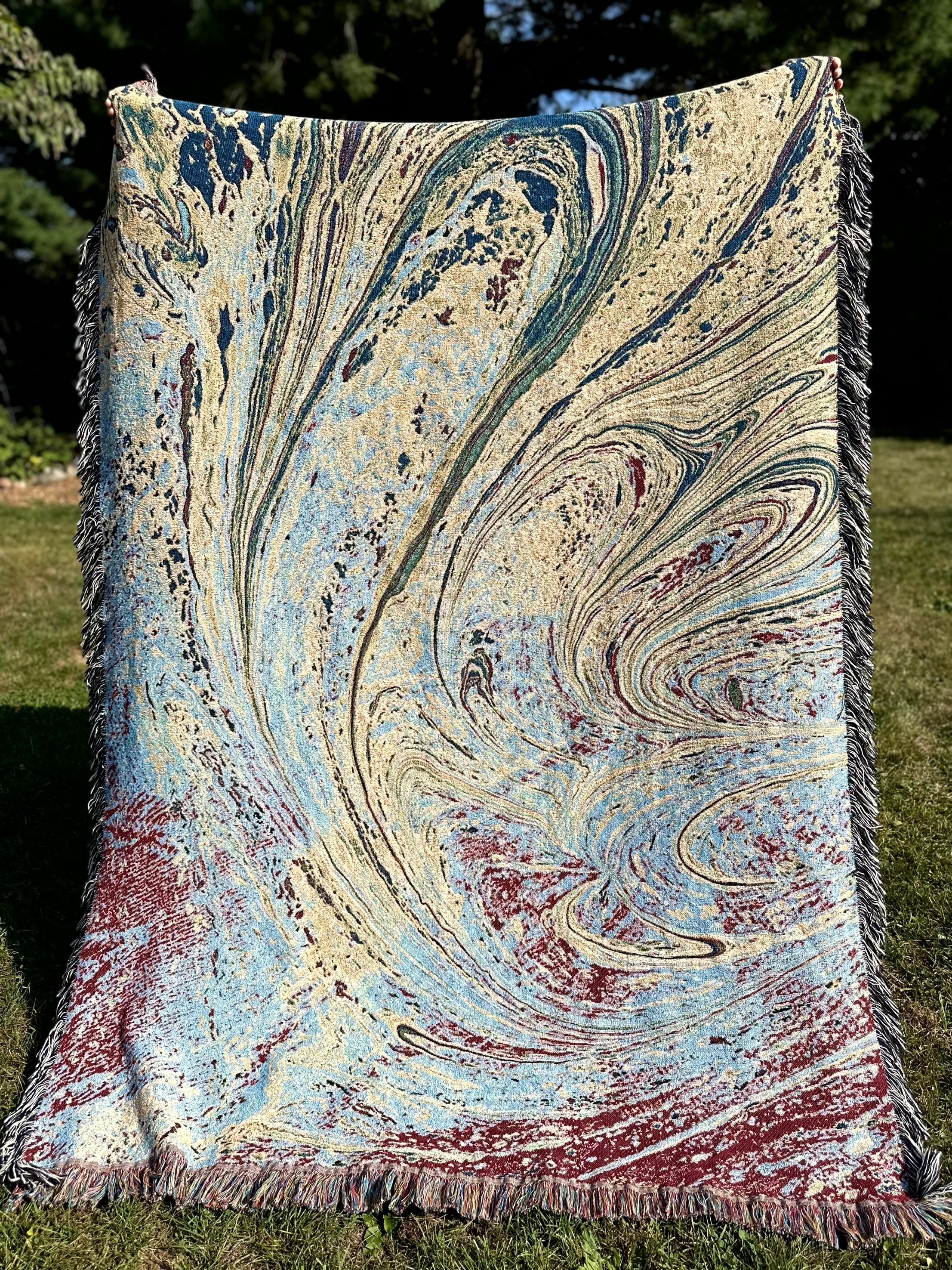 Kök Stüdyo woven cotton throw blanket with abstract pastel blue, cream, and maroon Ebru marbling pattern.