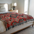Kök Stüdyo Moroccan Berber-inspired woven throw blanket in red, black, and cream with geometric patterns and fringe.