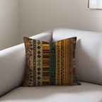 Kök Stüdyo African Ndelebe pattern woven throw pillow with geometric designs in earthy tones on a sofa.