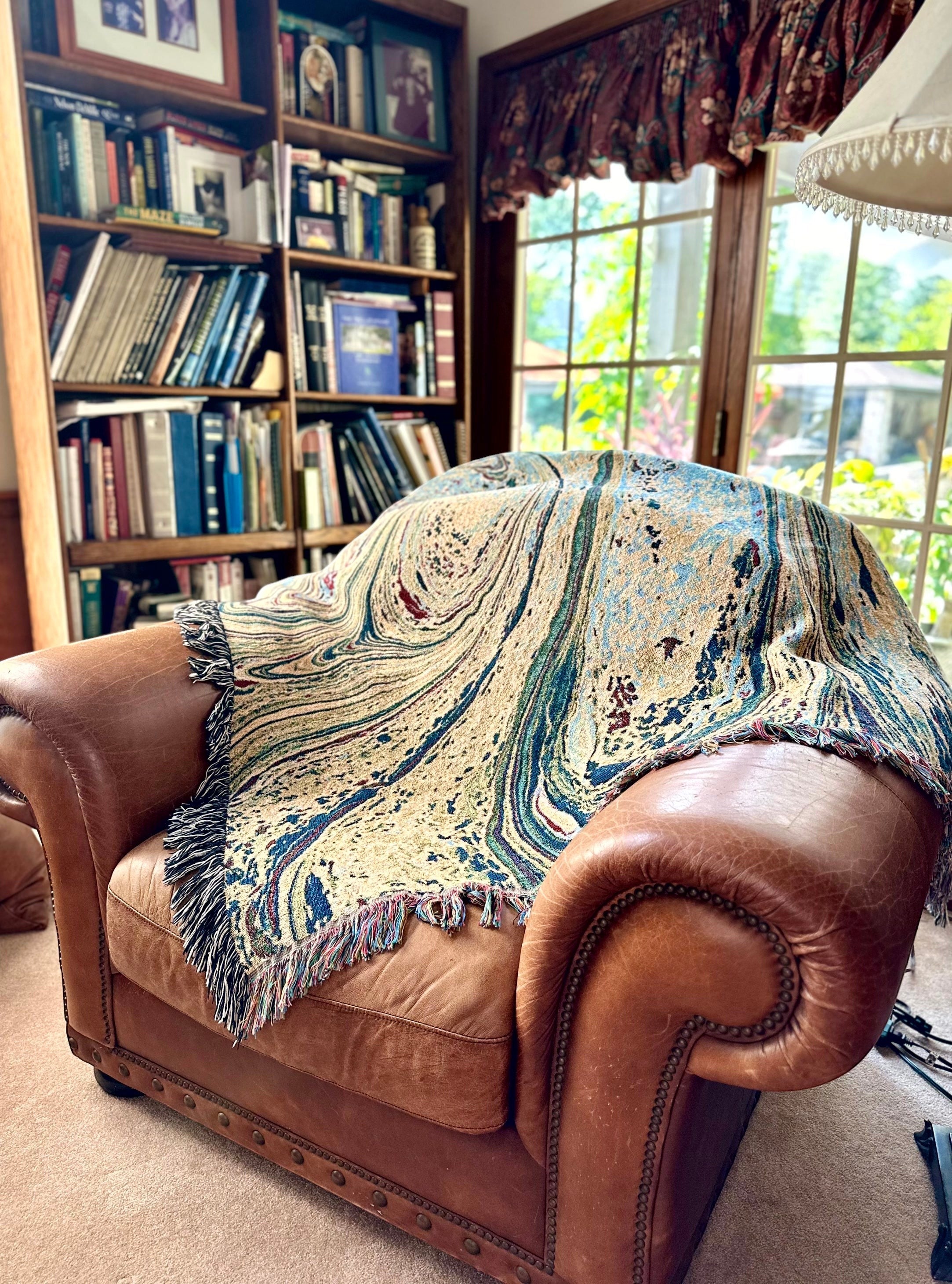 Kök Stüdyo woven cotton throw blanket with abstract pastel Ebru marbling pattern in beige, blue, and red.