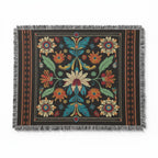 Kök Stüdyo woven blanket with Ojibwe-inspired floral art in red, yellow, blue, green on black. Cotton blend.