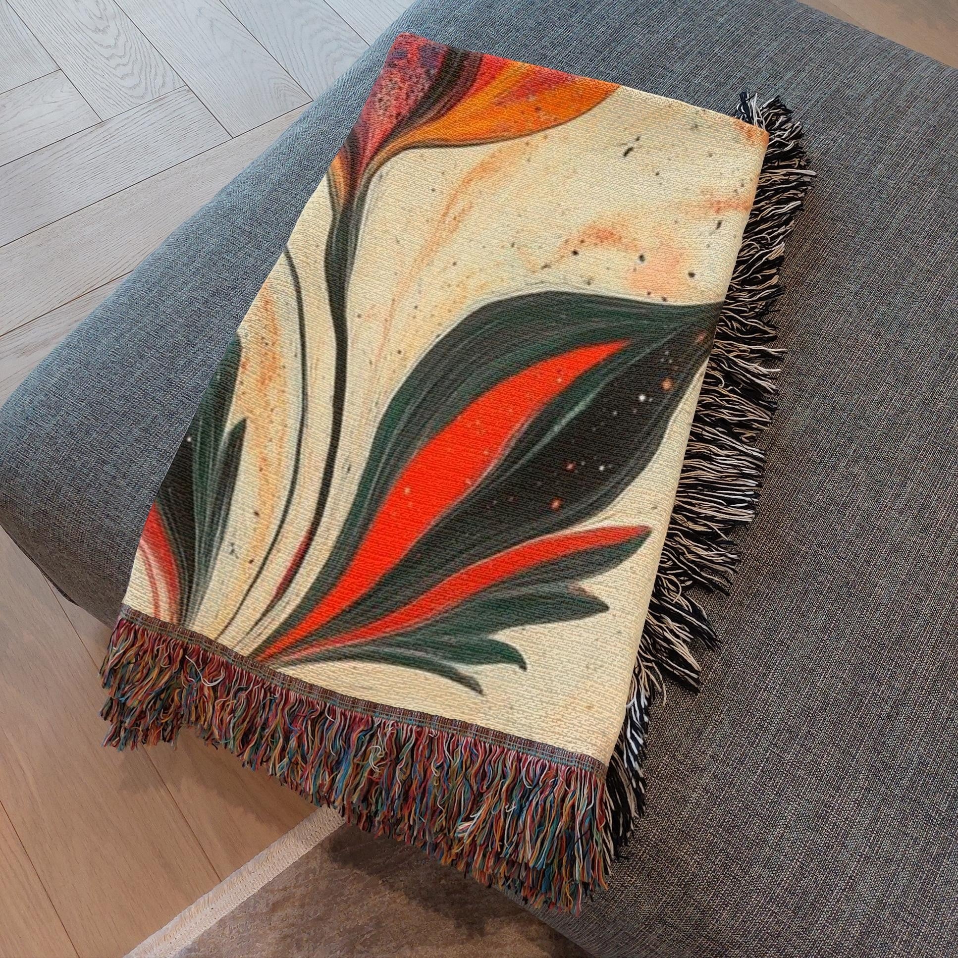 Kök Stüdyo woven throw blanket with a traditional Turkish marbling tulip design in vibrant orange, red, and dark green on a cream background.